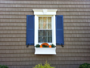 Brown siding and white window with blue shutters